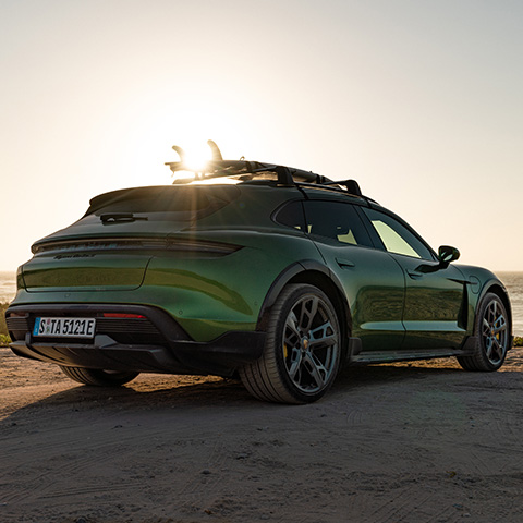 Green Porsche Taycan Cross Turismo with surfboard on roof