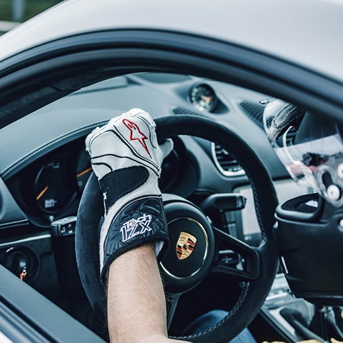 Left hand on Porsche steering wheel