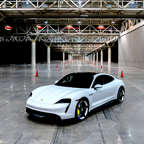 White Taycan Turbo S in large, empty exhibition hall