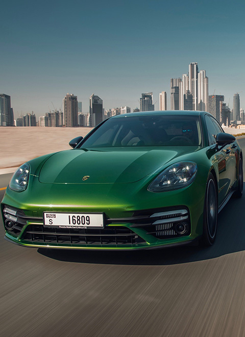 Green and red Panamera, side by side, Dubai skyline behind