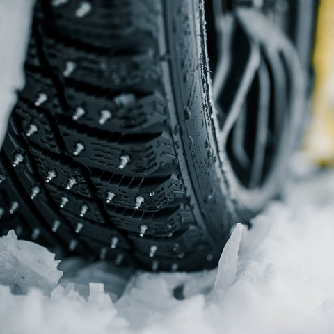 Detail of a car tire in the snow with spikes