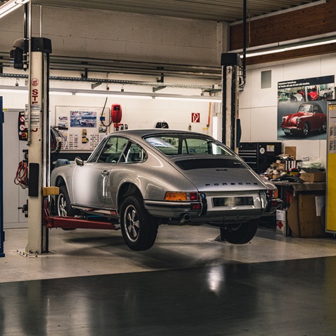 Classic 912 silver Porsche on car lift in restoration workshop