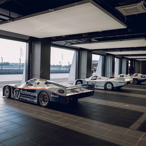 Group C Porsche endurance racing cars lined up in paddock