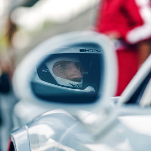 Image in door mirror of driver in race helmet