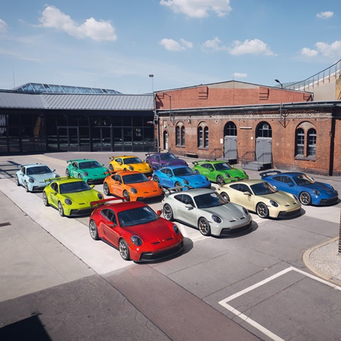 Porsche cars in spectrum of colours among industrial buildings