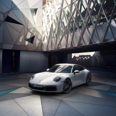 White Porsche 911 Carrera parked on colourful, geometric tiles