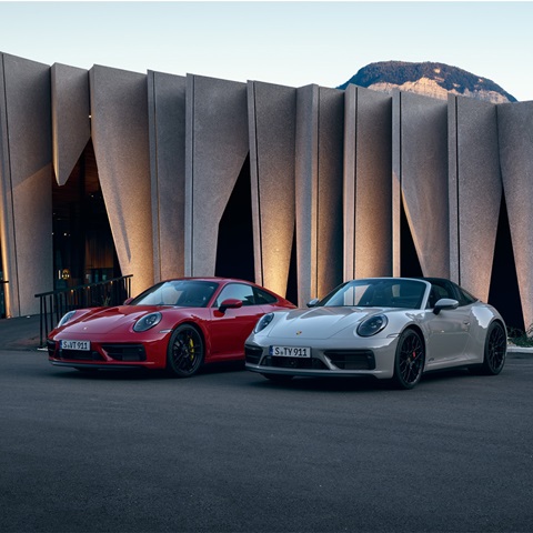 Front view of red Porsche and Grey Porsche in front of building
