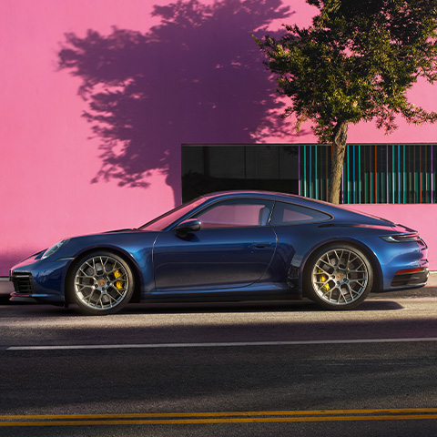 Blue Porsche 911 Carrera 4S in front of pink wall