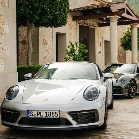 Line-up of Porsche 911 cars outside stone Mallorcan buildings