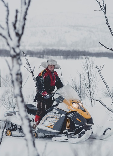Man in Sami costume on a snowmobile