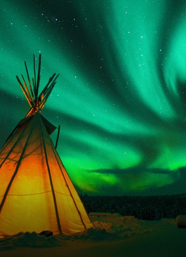 Teepee lit up in snow, Northern Lights in sky