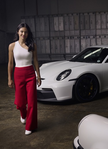 Emma Raducanu in locker room in front of white Porsche 911 GT3