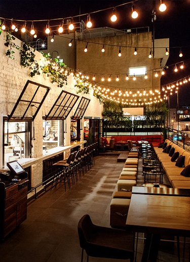 Hip rooftop bar decorated with garlands of white lightbulbs