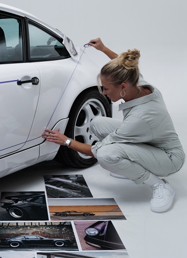 Artist marks reflective lines on white 964 Porsche with tape