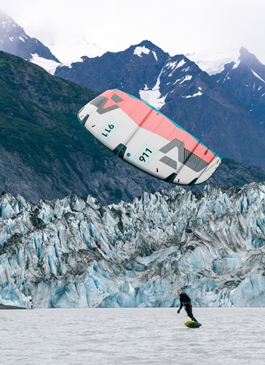 Kitesurfer on Alaskan waters, snowy mountains in background