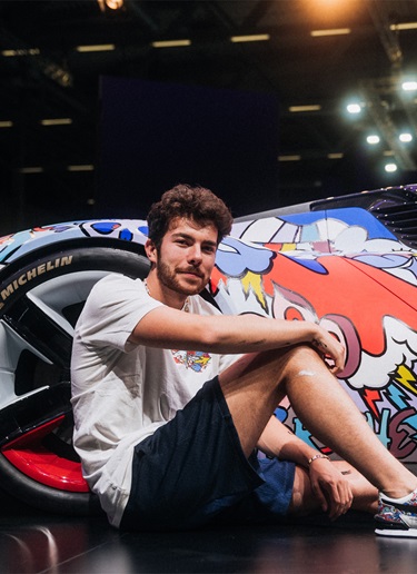 Artist Vexx sitting next to Porsche painted with colourful cartoons