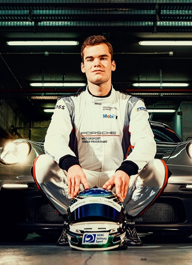 Laurin Heinrich in racing suit in front of Porsche racecar