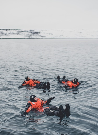 Three ice swimmers floating in the Arctic Ocean