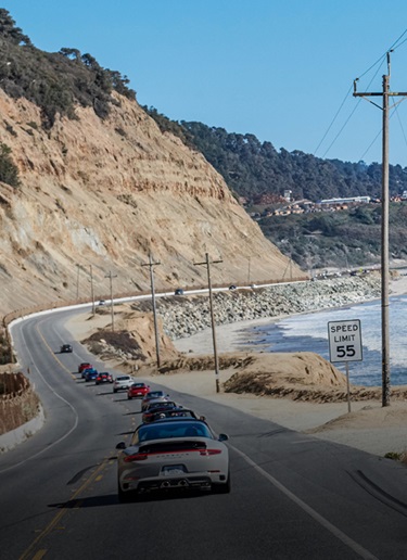 A coastal road between sandstone cliffs and surf-ready ocean