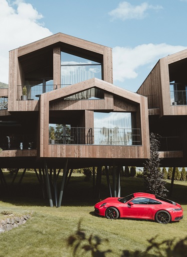 Red Porsche 911 parked in a meadow in modern wooden buildings