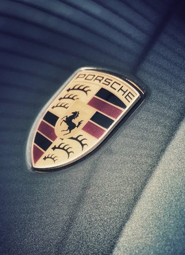 White-gloved hand taking Porsche crest out of case
