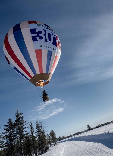 A hot air balloon flies over a snowy Finnish landscape